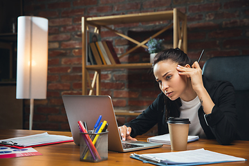 Image showing Young woman working in modern office using devices and gadgets. Making reports, analitycs, routine processing tasks