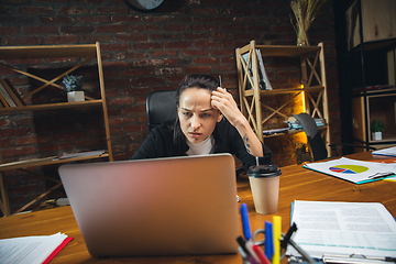 Image showing Young woman working in modern office using devices and gadgets. Making reports, analitycs, routine processing tasks