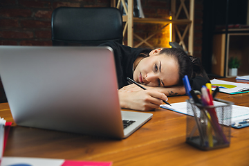 Image showing Young woman working in modern office using devices and gadgets. Making reports, analitycs, routine processing tasks