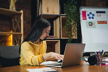 Image showing Young woman working in modern office using devices and gadgets. Making reports, analitycs, routine processing tasks