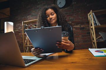 Image showing Young woman working in modern office using devices and gadgets. Making reports, analitycs, routine processing tasks