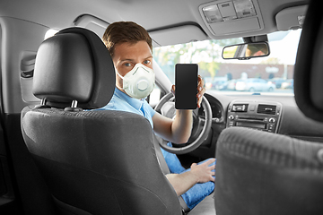 Image showing male car driver in mask showing smartphone