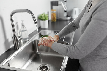 Image showing woman washing hands with liquid soap in kitchen