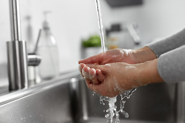 Image showing woman washing hands with liquid soap in kitchen