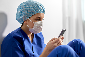 Image showing sad doctor or nurse in face mask with smartphone