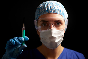 Image showing doctor in face mask and goggles holding syringe