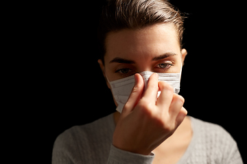 Image showing sick woman adjusting protective medical face mask