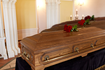 Image showing red rose flowers on wooden coffins in church