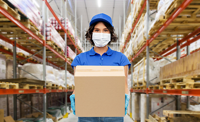 Image showing delivery woman in mask with box at warehouse