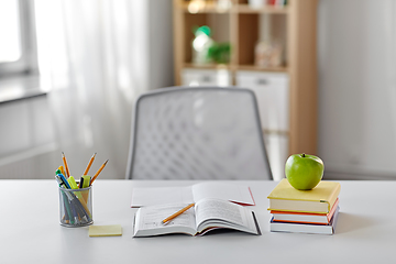 Image showing books, apple and school supplies on table at home