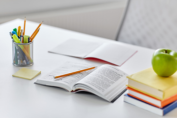 Image showing books, apple and school supplies on table at home