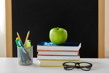 Image showing books, apple and school supplies on table at home