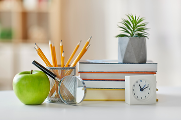 Image showing books, magnifier, pencils, apple on table at home