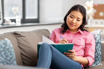 Image showing asian woman with diary sitting on sofa at home