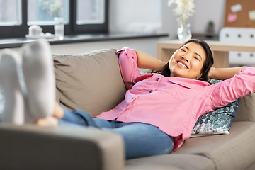 Image showing happy asian woman lying on sofa and dreaming