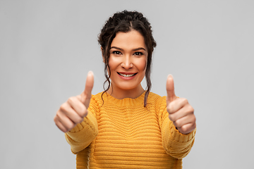 Image showing happy smiling young woman showing thumbs up