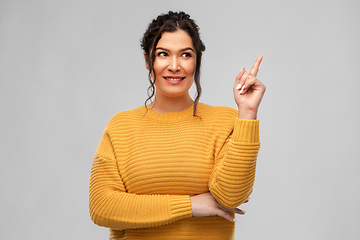 Image showing happy smiling young woman pointing finger up