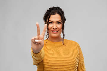 Image showing happy smiling young woman showing peace sign