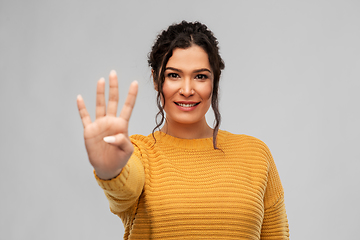 Image showing happy woman in pullover showing four fingers