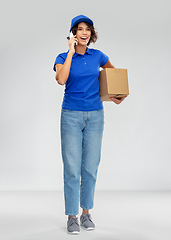 Image showing delivery woman with parcel calling on smartphone