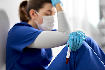 Image showing sad doctor or nurse holding beaker with blood test