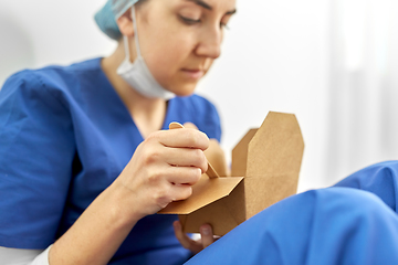 Image showing sad doctor or nurse eating takeaway food from box