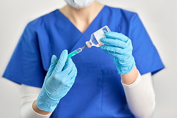 Image showing doctor in face mask with syringe and medicine