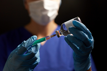 Image showing doctor in face mask with syringe and medicine