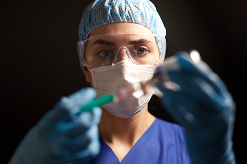 Image showing doctor in face mask with syringe and medicine