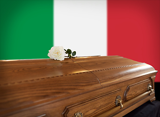 Image showing rose flower on wooden coffin over flag of italy