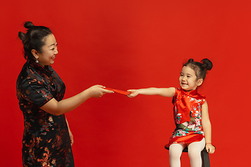 Image showing Happy Chinese New Year. Asian mother and daughter portrait isolated on red background