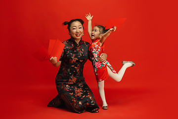 Image showing Happy Chinese New Year. Asian mother and daughter portrait isolated on red background