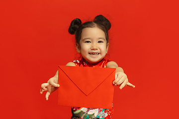 Image showing Happy Chinese New Year. Asian little girl portrait isolated on red background