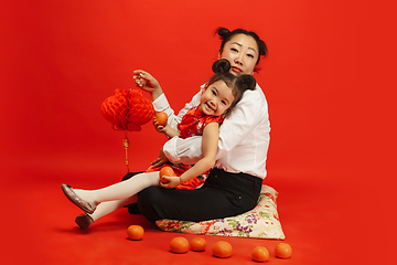 Image showing Happy Chinese New Year. Asian mother and daughter portrait isolated on red background