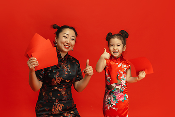 Image showing Happy Chinese New Year. Asian mother and daughter portrait isolated on red background