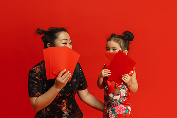 Image showing Happy Chinese New Year. Asian mother and daughter portrait isolated on red background