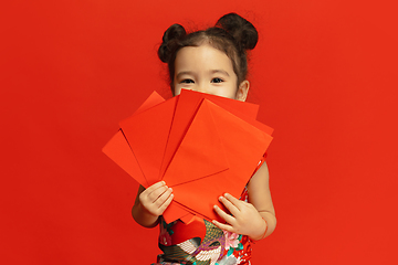 Image showing Happy Chinese New Year. Asian little girl portrait isolated on red background