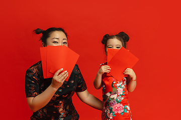 Image showing Happy Chinese New Year. Asian mother and daughter portrait isolated on red background