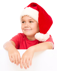 Image showing Little girl in santa hat is holding blank board