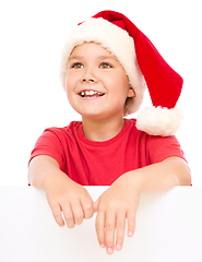 Image showing Little girl in santa hat is holding blank board