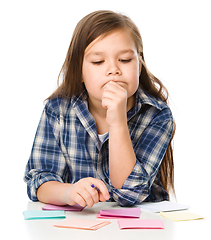 Image showing Girl is writing on color stickers using pen