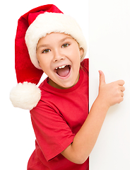 Image showing Little girl in santa hat is holding blank board