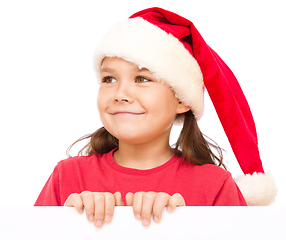 Image showing Little girl in santa hat is holding blank board