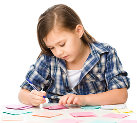 Image showing Girl is writing on color stickers using pen