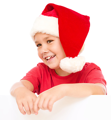 Image showing Little girl in santa hat is holding blank board