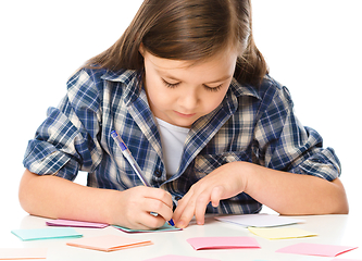 Image showing Girl is writing on color stickers using pen