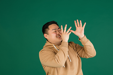 Image showing Asian man\'s portrait isolated over green studio background with copyspace