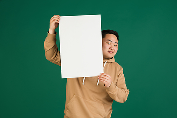 Image showing Asian man\'s portrait isolated over green studio background with copyspace