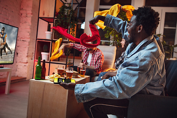 Image showing Group of friends watching TV, sport match together. Emotional fans cheering for favourite team, watching on exciting game. Concept of friendship, leisure activity, emotions