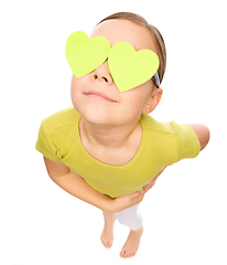 Image showing Little girl is holding hearts over her eyes